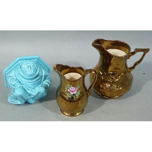 203 - Two copper lustre jugs and a turquoise glazed wall sconce modelled as a monk