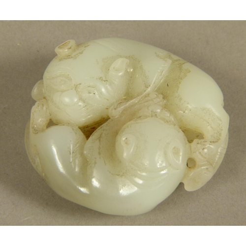 103 - A CHINESE CELADON JADE CARVING of two intertwined dogs, 5.5cm diameter