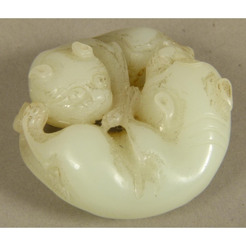 103 - A CHINESE CELADON JADE CARVING of two intertwined dogs, 5.5cm diameter