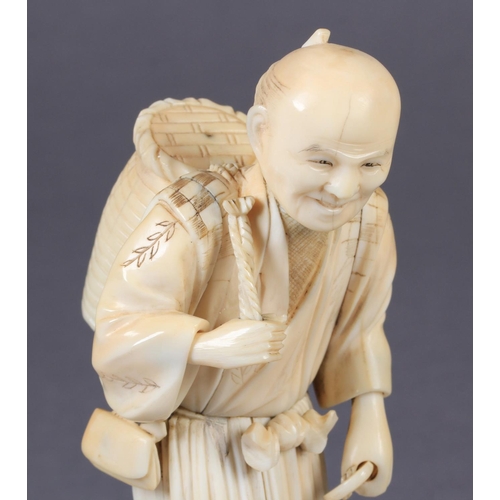 113 - A JAPANESE IVORY OKIMONO OF A FISHERMAN, standing, a basket on his back and a hook in his hand, two ... 