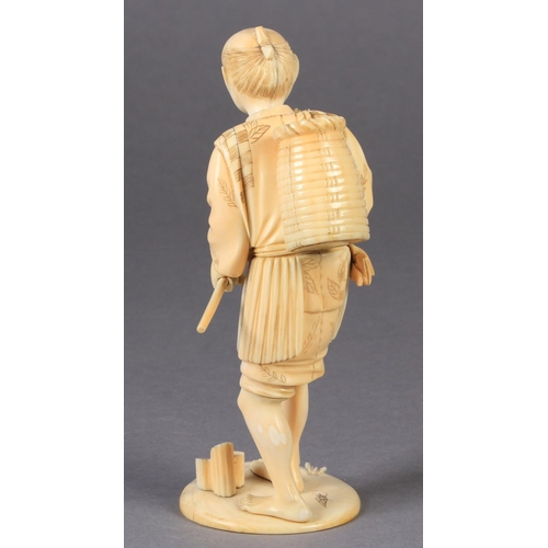 113 - A JAPANESE IVORY OKIMONO OF A FISHERMAN, standing, a basket on his back and a hook in his hand, two ... 