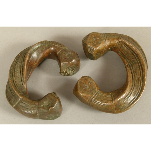 125 - A PAIR OF BRONZE PENANNULAR BRACELETS each with square faceted terminals, bands of geometric decorat... 