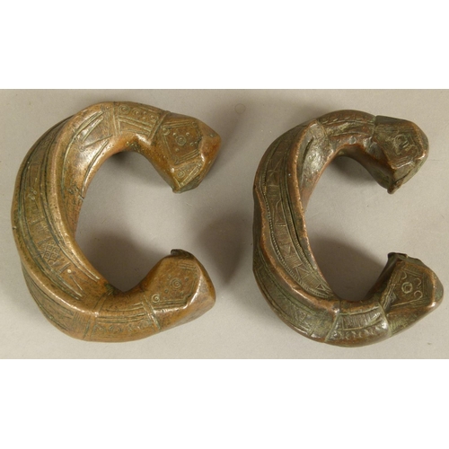 125 - A PAIR OF BRONZE PENANNULAR BRACELETS each with square faceted terminals, bands of geometric decorat... 