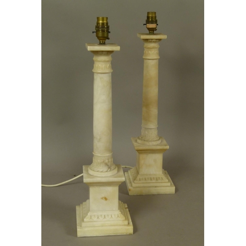 21 - A PAIR OF ALABASTER COLUMN TABLE LAMPS with lobed and palmette carved capitals and conforming bases,... 