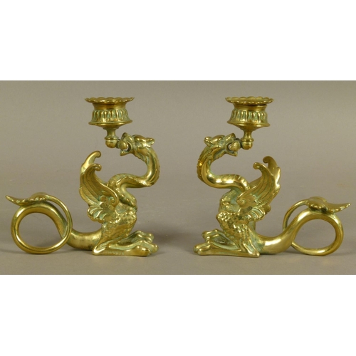 27 - A PAIR OF VICTORIAN BRASS CANDLESTICKS in the form of a dragon holding the sconce in its mouth, its ... 