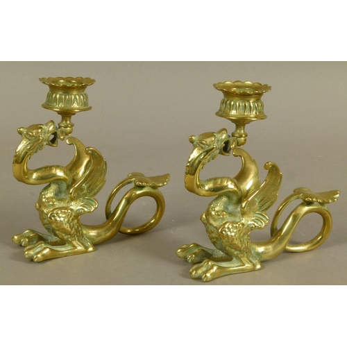 27 - A PAIR OF VICTORIAN BRASS CANDLESTICKS in the form of a dragon holding the sconce in its mouth, its ... 