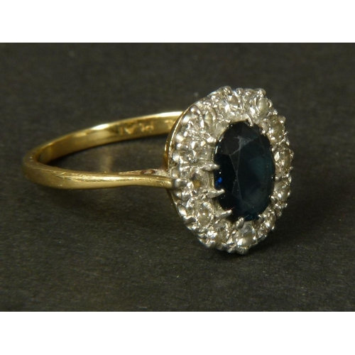 344 - A SAPPHIRE AND DIAMOND CLUSTER RING, the oval faceted sapphire claw set within a surround of brillia... 