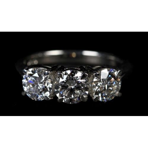 355 - A THREE STONE DIAMOND RING in platinum, the graduated brilliant cut stones claw set in line, total a... 