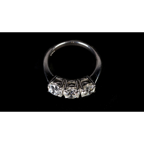 355 - A THREE STONE DIAMOND RING in platinum, the graduated brilliant cut stones claw set in line, total a... 