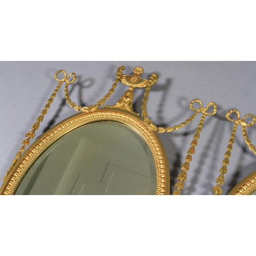 484 - A PAIR OF EDWARD VII GILT WALL MIRRORS the oval bevelled plate within a beaded frame with urn and ri... 