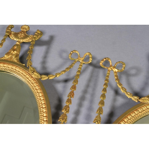 484 - A PAIR OF EDWARD VII GILT WALL MIRRORS the oval bevelled plate within a beaded frame with urn and ri... 