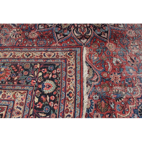 490 - A MASHAD CARPET, North East Persia, the burgundy field with a blue floral star medallion to the cent... 