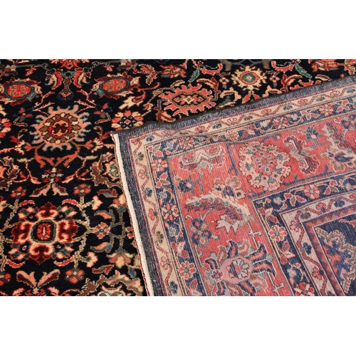 493 - A PERSIAN CARPET, Nenej Southern Hamadam Region the dark blue ground filled with plant forms in rose... 