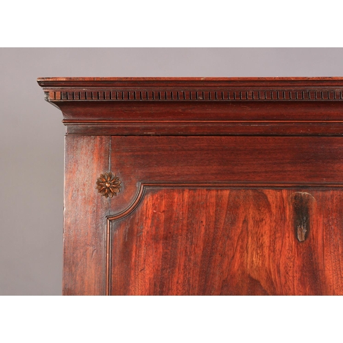 512 - A GEORGE III MAHOGANY CLOTHES PRESS the concave cornice having dentil moulding, above two figured do... 