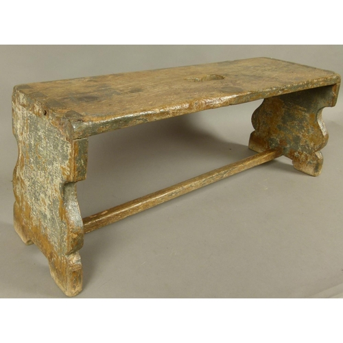 566 - A LATE 18TH/EARLY 19TH CENTURY ELM LONG STOOL the top with kidney shaped carrying handle, flat balus... 