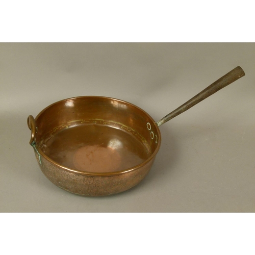 571 - A LARGE COPPER PAN 19th century, circular, having a tapering hollow iron handle and copper loop hand... 