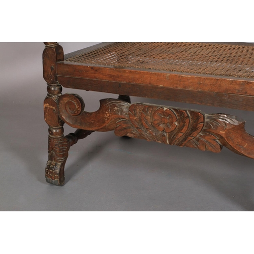 581 - A CHARLES II BEECHWOOD DAY BED, the bergere caned end panel within a foliate carved frame with turne... 