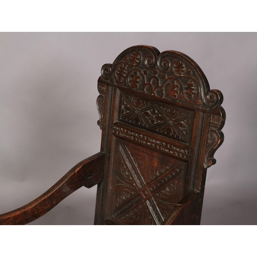 594 - AN OAK PANEL BACK ARMCHAIR, 17th century and later, the cresting carved with scrolling foliage on a ... 