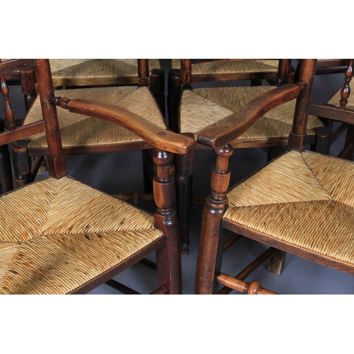 612 - A SET OF TEN ELM SPINDLE BACK RUSH SEATED DINING CHAIRS, early 19th century, on rounded legs and tur... 