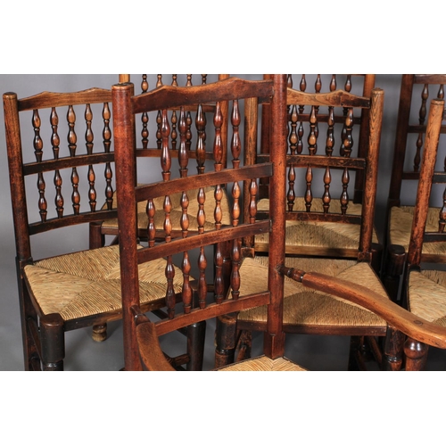 612 - A SET OF TEN ELM SPINDLE BACK RUSH SEATED DINING CHAIRS, early 19th century, on rounded legs and tur... 