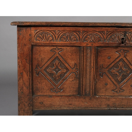 617 - A LATE 17TH CENTURY OAK KIST the hinged single plank top with moulded lip above a lunettes carved fr... 