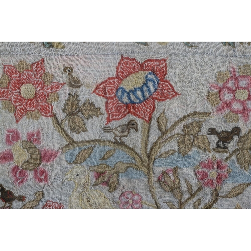 7 - AN 18TH CENTURY NEEDLEWORK PANEL of birds amongst flowering branches within a border of trailing flo... 