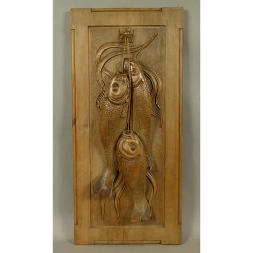 77 - AN ARTS AND CRAFTS PANEL FINELY CARVED WITH THREE HUNG FISH, realistically detailed with textured ba... 