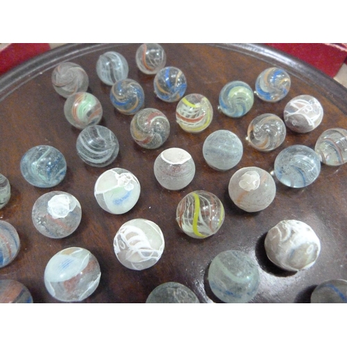 7 - An early 20th century solitaire game with turned walnut board and thirty-three marbles (some affecte... 