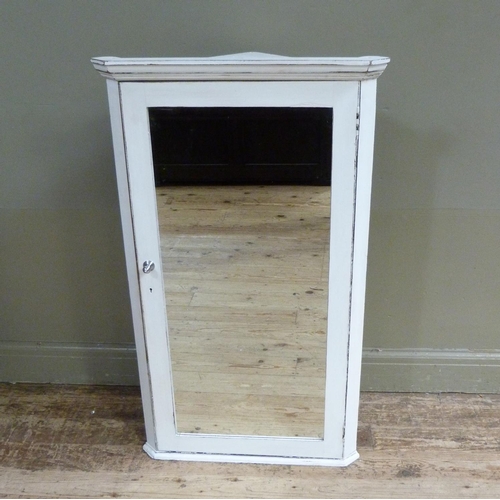 122 - A white painted wooden hanging corner cabinet with flared cornice above a mirrored door, 114cm high