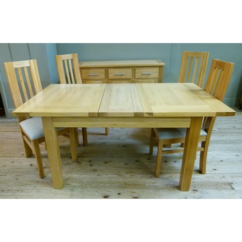 134 - An oak extending dining table, together with a set of four rail back dining chairs with oatmeal colo... 