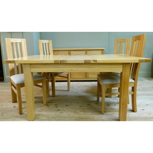 134 - An oak extending dining table, together with a set of four rail back dining chairs with oatmeal colo... 
