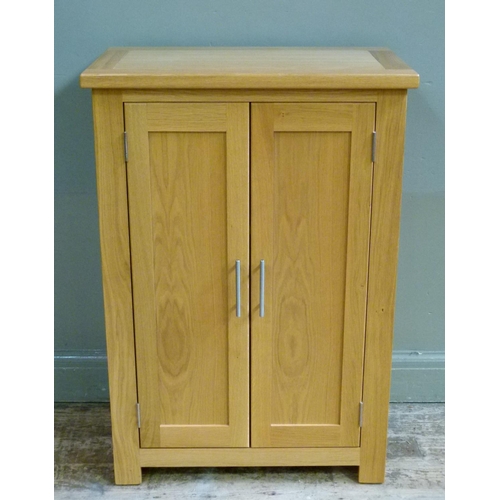 137 - A reproduction oak cupboard enclosed by a pair of panelled cupboard doors, 70cm wide x 102cm high