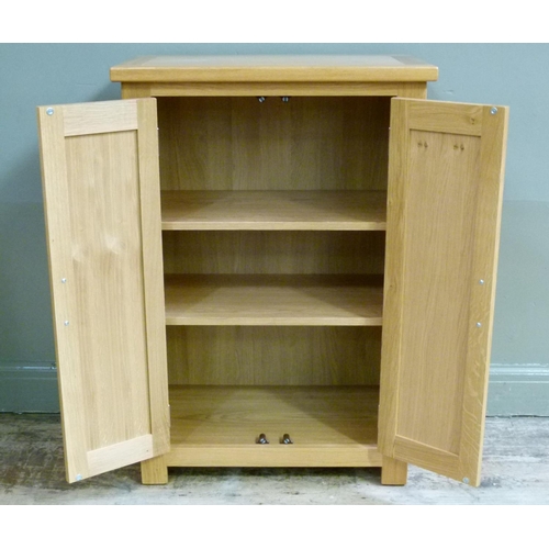 137 - A reproduction oak cupboard enclosed by a pair of panelled cupboard doors, 70cm wide x 102cm high
