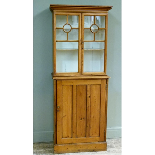 396 - A Victorian stripped pine cupboard the flared cornice above a pair of glazed doors applied with moul... 