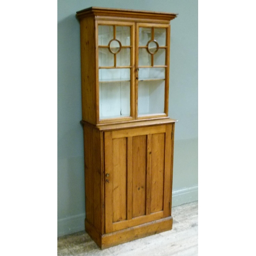 396 - A Victorian stripped pine cupboard the flared cornice above a pair of glazed doors applied with moul... 
