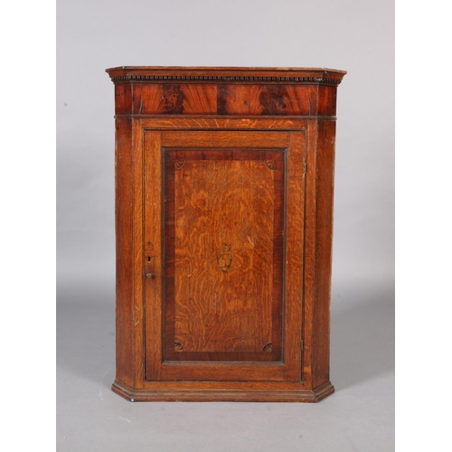 123 - A George III oak hanging corner cupboard with dentil moulded cornice, the single panelled door revea... 