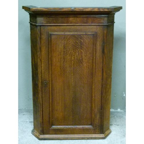 124 - A George III oak hanging corner cupboard with flared cornice and mahogany veneered frieze, panelled ... 