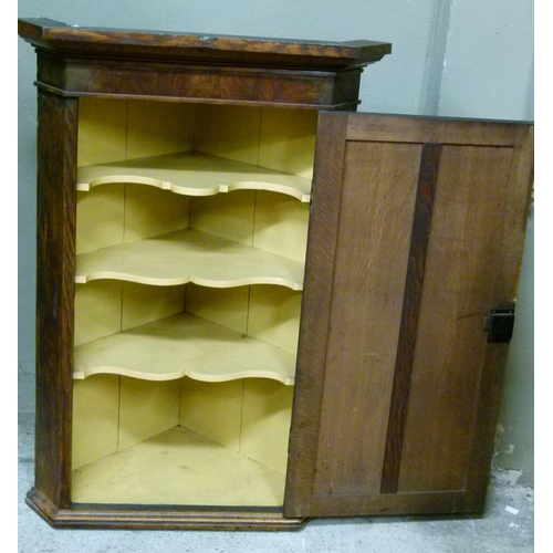 124 - A George III oak hanging corner cupboard with flared cornice and mahogany veneered frieze, panelled ... 