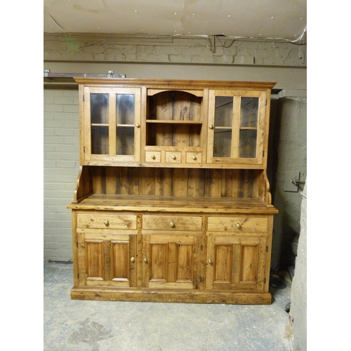 130 - A reproduction pine dresser with flared cornice, the back with central shelf, three small drawers fl... 