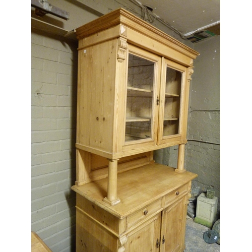 131 - A Continental pine cabinet with flared cornice above a pair of glazed doors, panelled back and proje... 