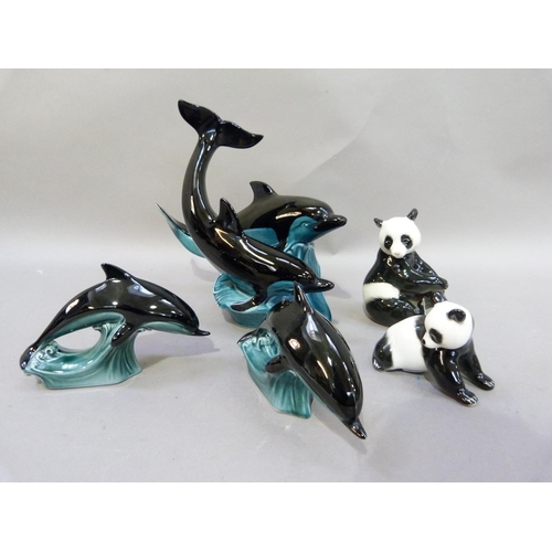 24 - A pair of Russian porcelain panda bear figures, 13cm high; together with three Poole pottery dolphin... 