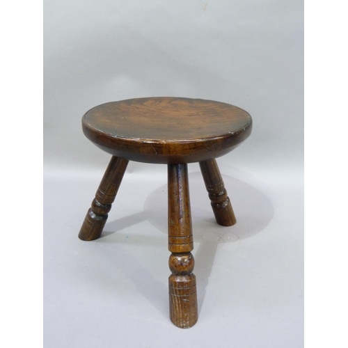 55 - An elm stool, circular dished dished seat on three turned legs, 28cm D x 29cm H