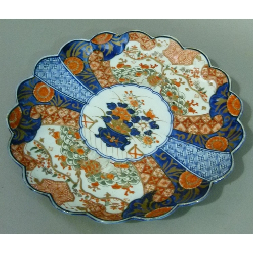 66 - A Japanese Imari petal shaped dish decorated in typical palette, the centre with vase of flowers wit... 