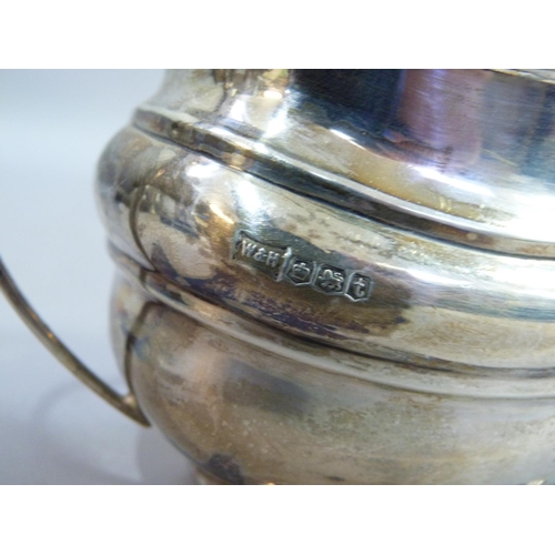 235 - A George V silver oblong sauce boat with gadroon rim, on four ball feet by Walker & Hall Ltd, Sheffi... 