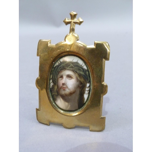 242 - A head and shoulders portrait of Christ, printed on ceramic plaque held within a brass frame with cr... 