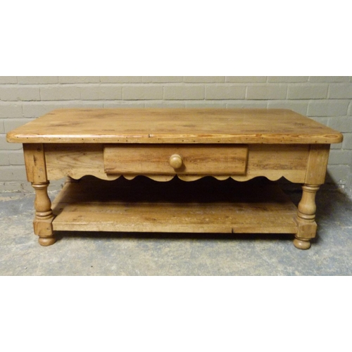 149 - A pine two tier coffee table, the rounded rectangular top above a shaped frieze fitted with one shor... 