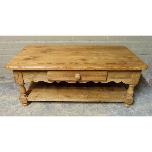 149 - A pine two tier coffee table, the rounded rectangular top above a shaped frieze fitted with one shor... 