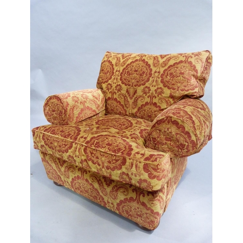 330 - An oversized armchair upholstered in  old gold and russet fabric and on circular feet