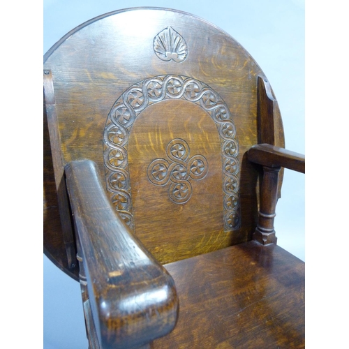 264 - A 1920/30's oak monks chair, the arch back carved with guilloche and folding over to create a table,... 