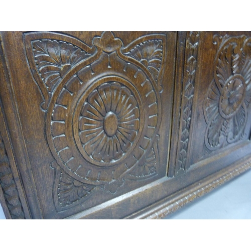 326 - An oak kist having a partial lift up top above a triple paneled front carved with oval medallions an... 